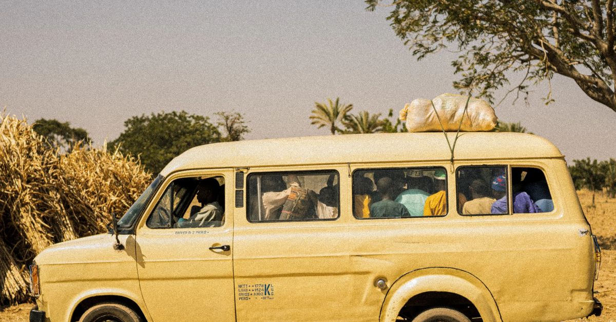 Minibus de livraison propre circulant dans une rue passante et ensoleillée d'une grande ville marocaine.